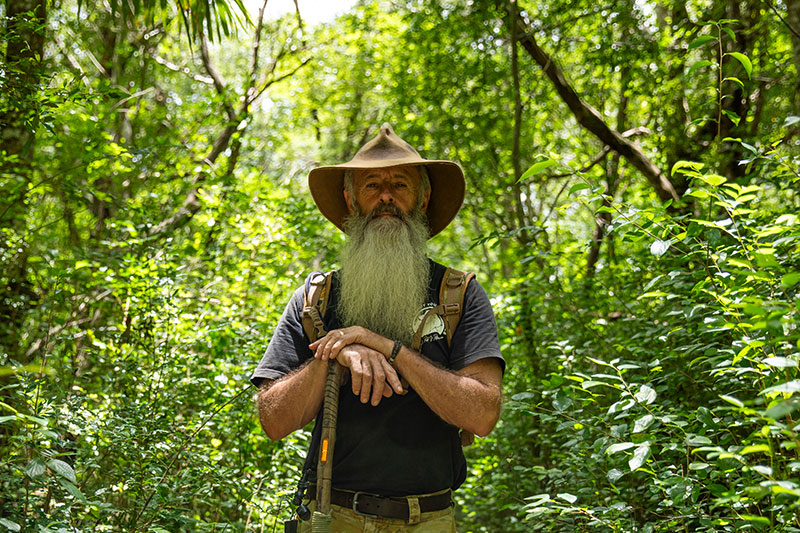 Rick Peterson standing among trees in the bush. 