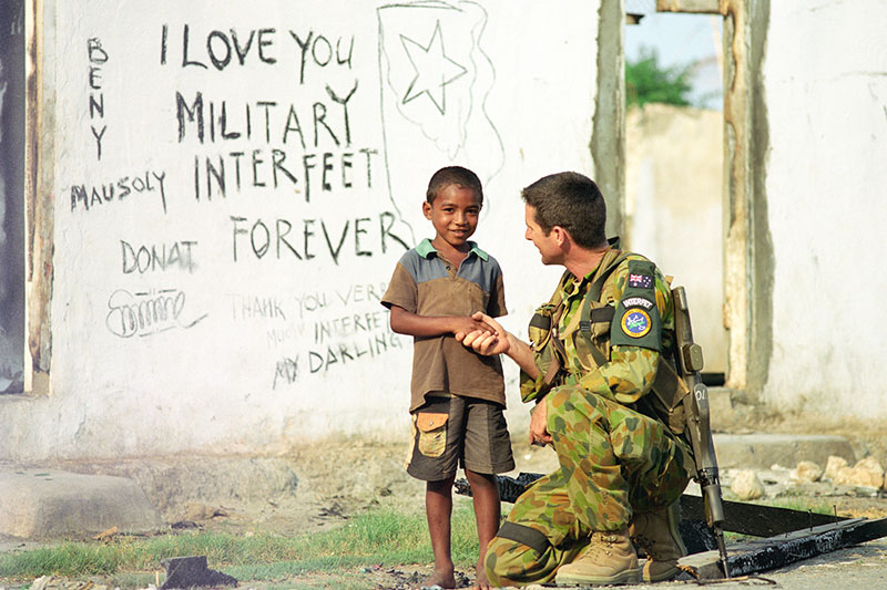 Image: Defence Australia | Army Sergeant Martin Ryan shakes hand with an East Timorese child.